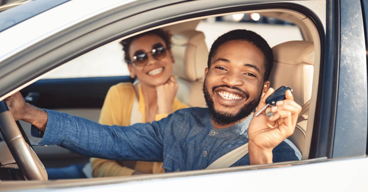 A person holding up their car keys in the car smiling