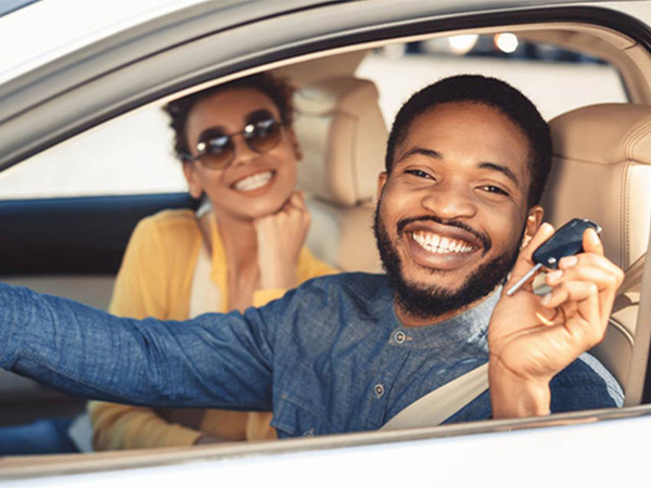 Two people in a car smiling holding up car keys
