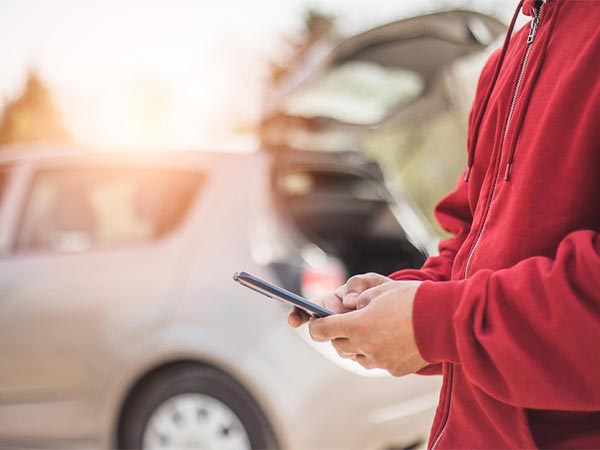a person standing besides a car on their phone