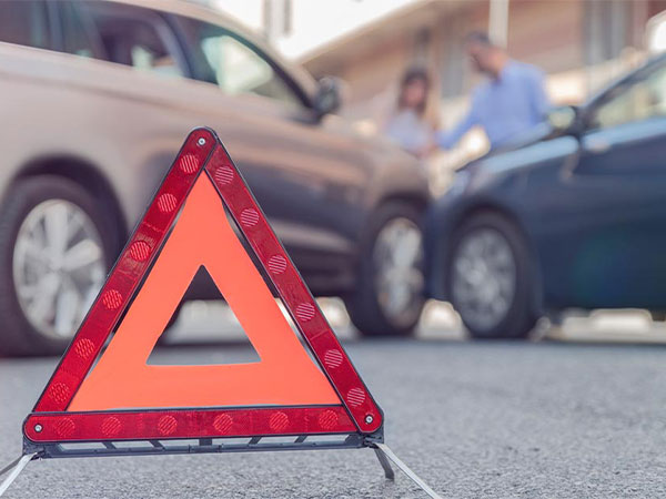 a traffic caution triangle sign on the floor in front of a car accident