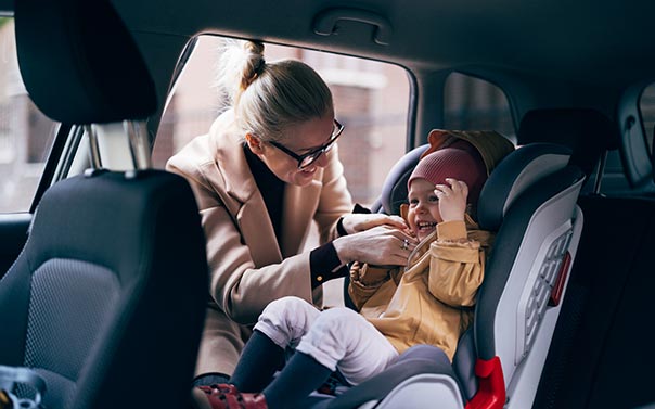 mom buckling baby in carseat